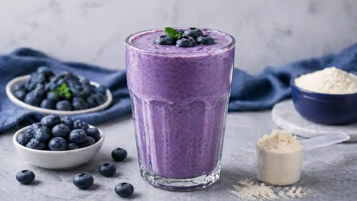 Thick blueberry protein shake in a glass, made with fresh blueberries and topped with creamy texture, refreshing healthy smoothie