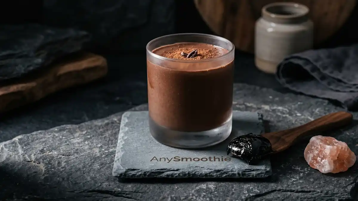 Rich chocolate smoothie in a minimalist glass featuring the AnySmoothie logo, paired with pure black shilajit resin on a wooden spatula and raw Himalayan rock to highlight shilajit smoothies for fulvic acid minerals.